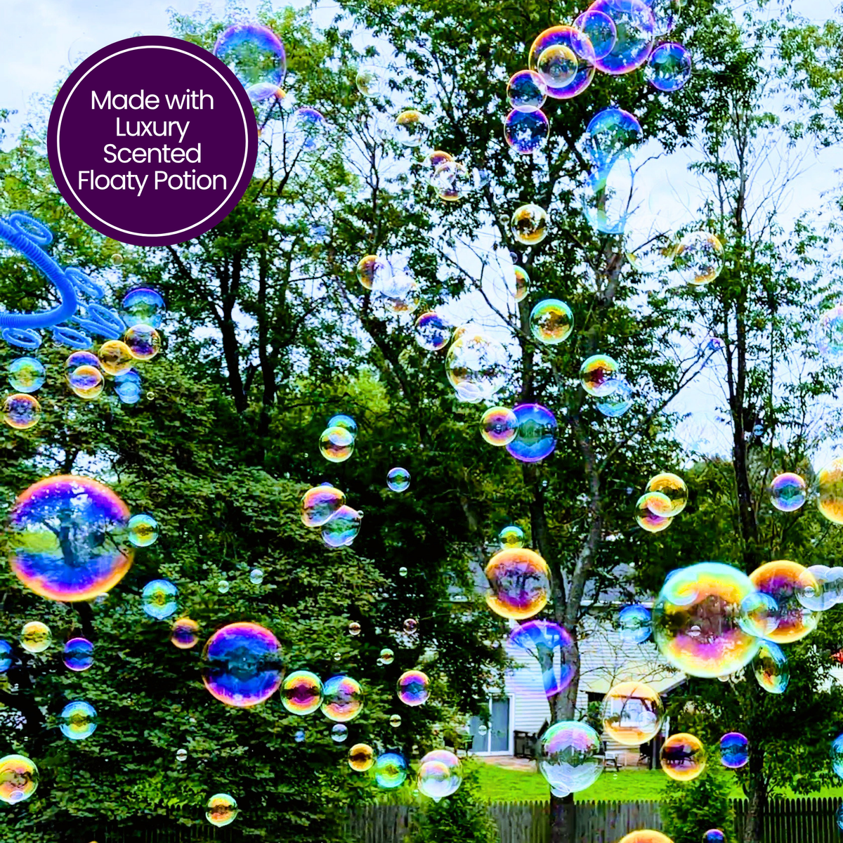 A cloud of colorful, iridescent floating bubbles drifting through a sunny backyard treescape, created with One Two Celebrate® Luxury Scented Floaty Potion.